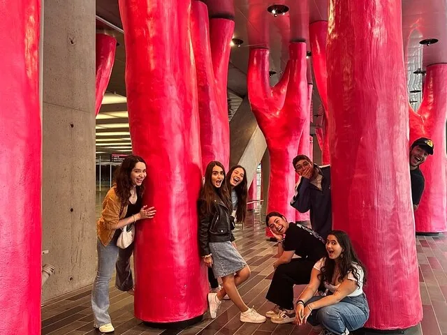 Group of people posing by bright pink tree-like columns