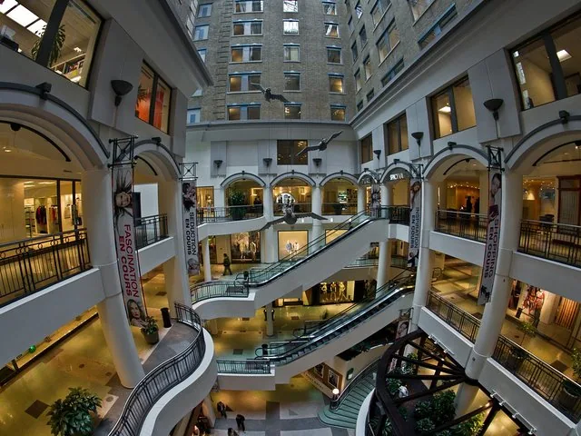 Multi-level indoor shopping mall with escalators and flying bird decor