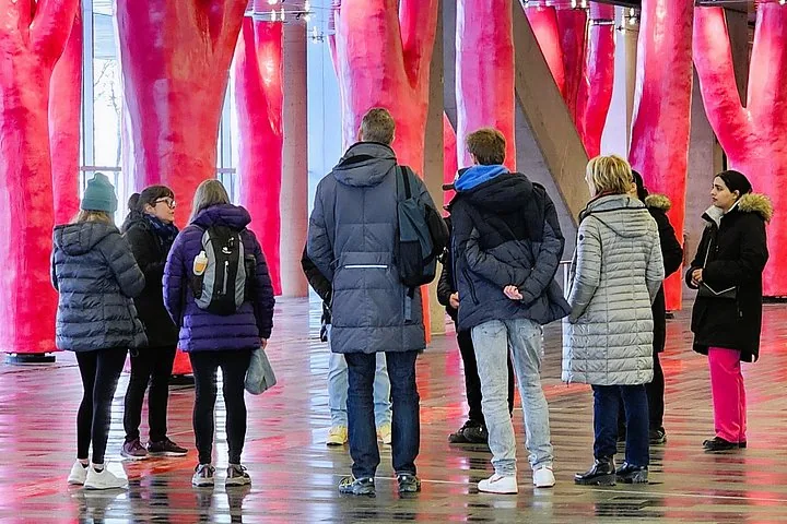 Tour group listening to guide among pink tree-like columns