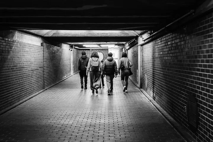 Black and white photo of people walking in a tunnel